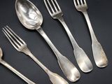six silver spoons and a fork on a black surface
