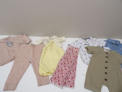 Plusieurs vêtements pour bébés sont disposés sur une table devant un mur.