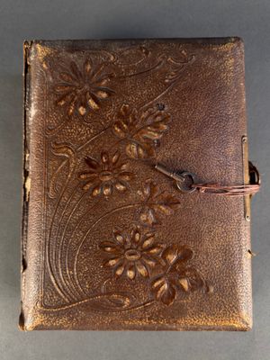 un vieux livre relié en cuir avec un motif floral sur la couverture