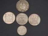 five different coins are arranged in a row on a black surface