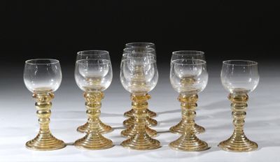 six verres à vin dorés sont alignés sur une surface blanche