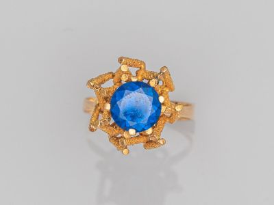 gros plan d'une bague en or avec une pierre bleue au centre