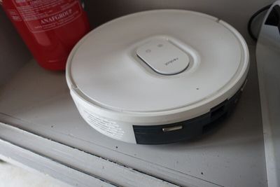 un robot blanc posé sur une étagère, à côté d'un extincteur
