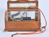 une boîte à musique à l'ancienne, munie d'un cordon rouge et d'un fil métallique