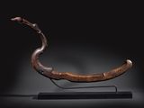 une photo d'une sculpture en bois représentant un serpent, posée sur un socle