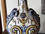 un vase posé sur une table, avec un tableau en arrière-plan