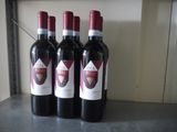 three bottles of red wine are lined up on a counter