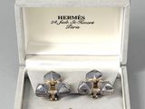 pair of silver and gold cufflinks in a box on a white surface