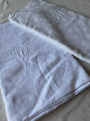 Deux serviettes blanches monogrammées sont posées sur un lit.