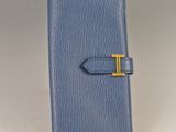 a blue leather wallet with a gold t on the front