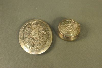 deux boutons anciens en laiton posés sur une table avec un fond vert