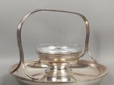 un plat ancien en argent surmonté d'un support en verre