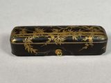 a small black and gold box with gold flowers on it