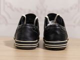 pair of black leather shoes with white soles sitting on a wooden table