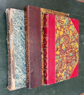 three old books are stacked on top of each other on a table