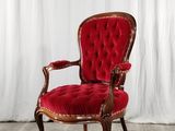 une chaise rouge posée sur un parquet, à côté d'un rideau blanc