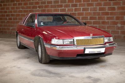 a red car that is parked in front of a brick wall