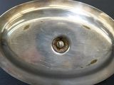 a silver plate with a hole in it on a black surface