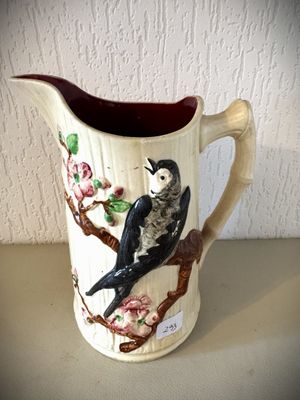 un pichet orné d'un oiseau, posé sur une table