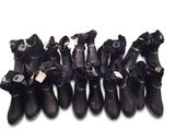 Plusieurs paires de bottes en cuir noir sont alignées sur une surface blanche