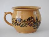 a brown cup with black flowers on it on a white surface