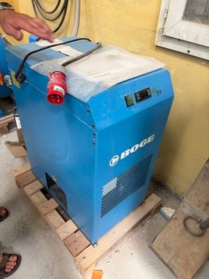 a man standing next to a blue machine on a pallet