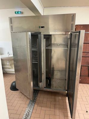 a stainless steel refrigerator in the middle of a tiled floor