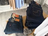 several pairs of jeans are stacked on a chair in a clothing store