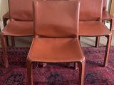 four brown leather chairs sitting on top of a rug on a carpeted floor