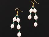 a pair of earrings with pearls and emerald beads