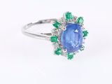 un gros plan d'une bague sertie d'un saphir bleu et d'une émeraude sur fond blanc