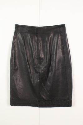 une jupe en cuir noir accrochée à un mur blanc