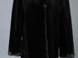 Le manteau est noir et est orné d'un col en fourrure.