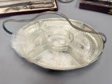 a silver tray with a handle on a table next to other silverware