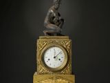 une statue d'un homme assis au sommet d'une horloge
