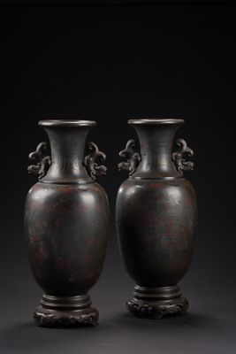 une paire de vases en bronze sur un socle, sur fond noir