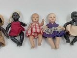 five black dolls are lined up in a row on a white surface