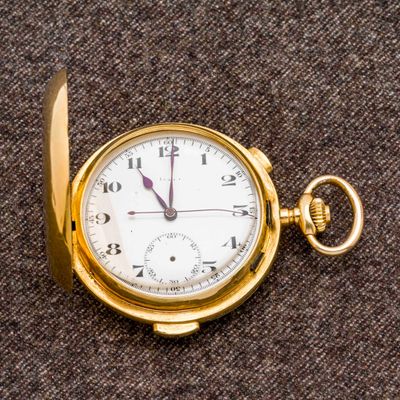 une montre de poche en or posée sur un tissu marron