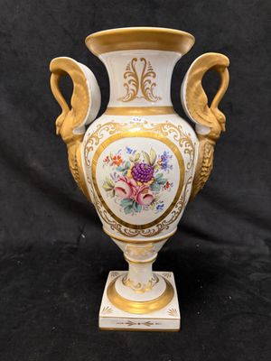 un vase blanc orné d'une bordure dorée et de motifs floraux