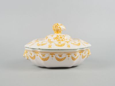 a white and gold covered dish with a bird on top