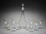 six verres à vin et une carafe posés sur une table