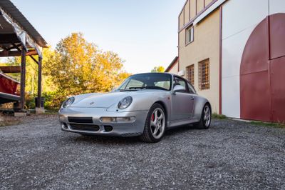 une voiture de sport argentée garée devant un immeuble