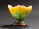 a yellow and green flower shaped vase on a black surface