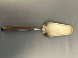 an antique silver plated shovel with a handle on a gray surface
