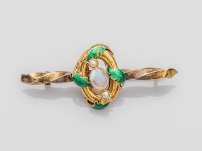 an image of a gold ring with a white stone and green leaves