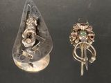 deux bagues en argent et une broche en argent posées sur un fond noir