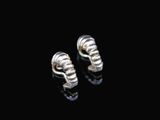 a pair of silver earrings sitting on top of a black surface