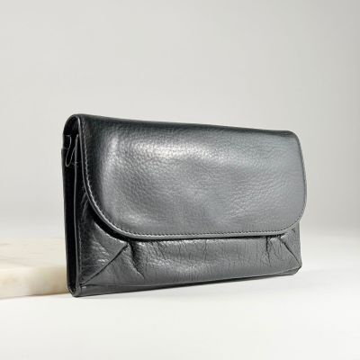 La pochette en cuir noir est posée sur une dalle de marbre