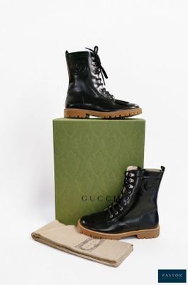 des bottes en cuir noir à lacets et avec un carré, sur fond blanc