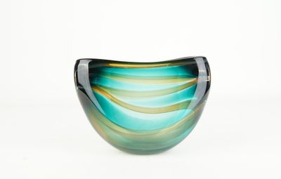 un bol en verre bleu et vert posé sur une surface blanche